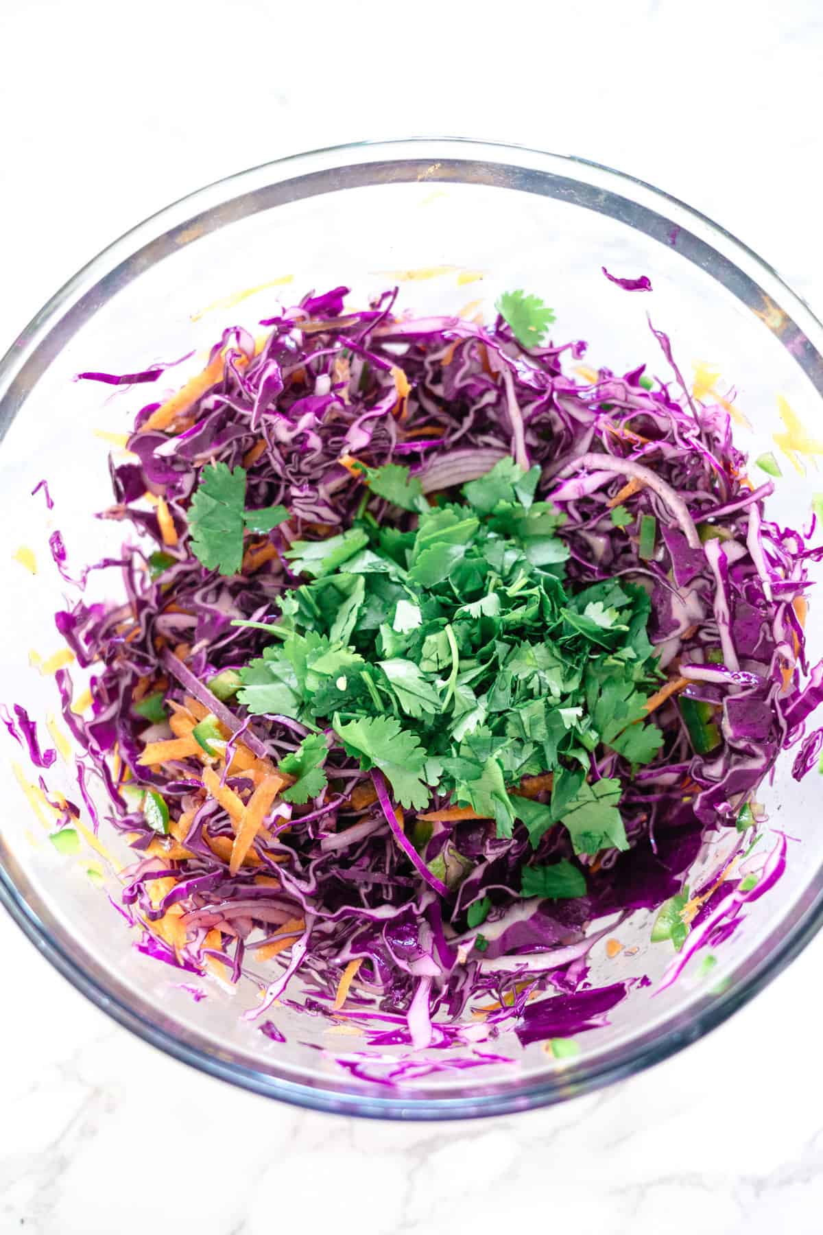 Purple cabbage slaw in a glass bowl.