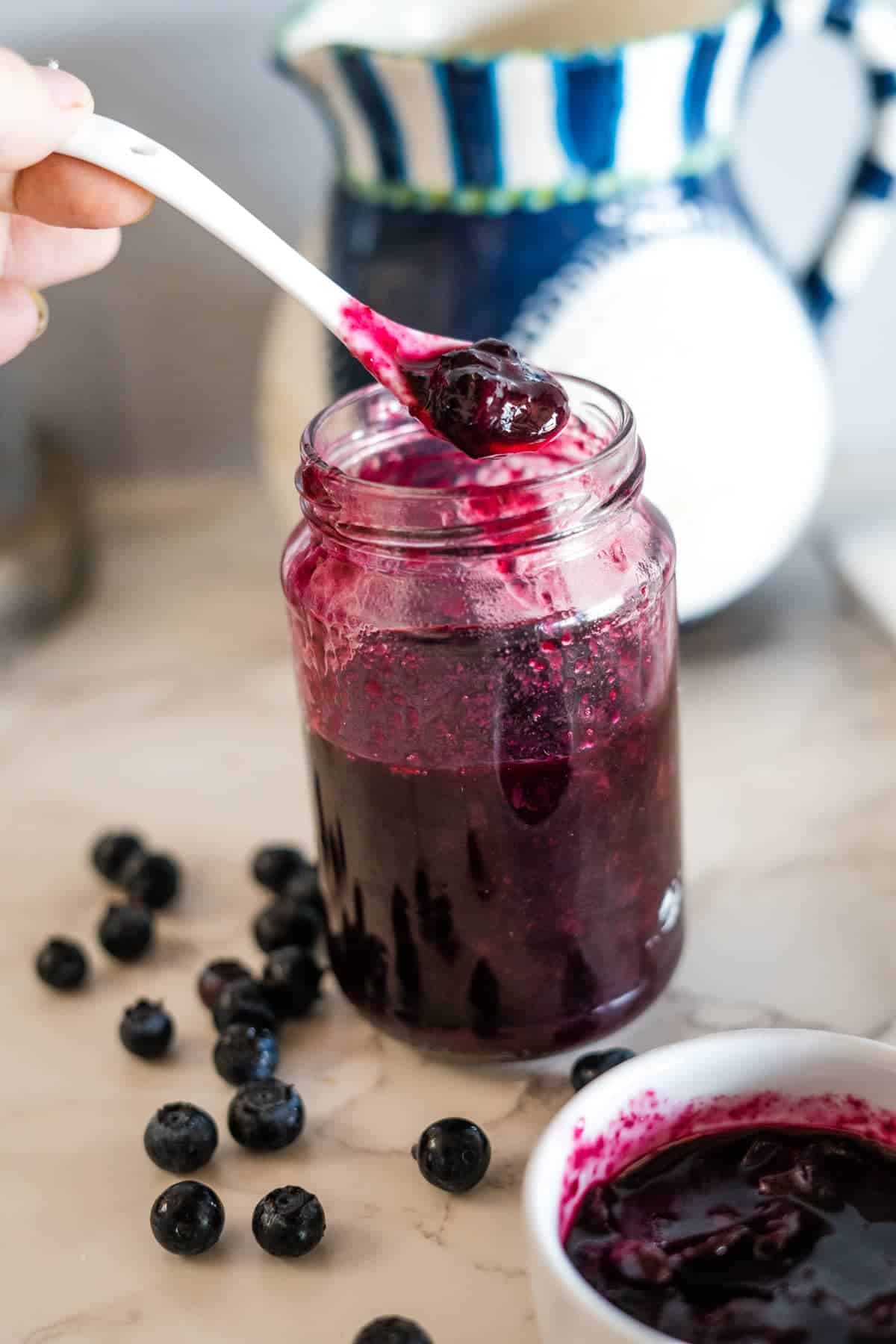 Keto blueberry sauce in a jar with a spoon.