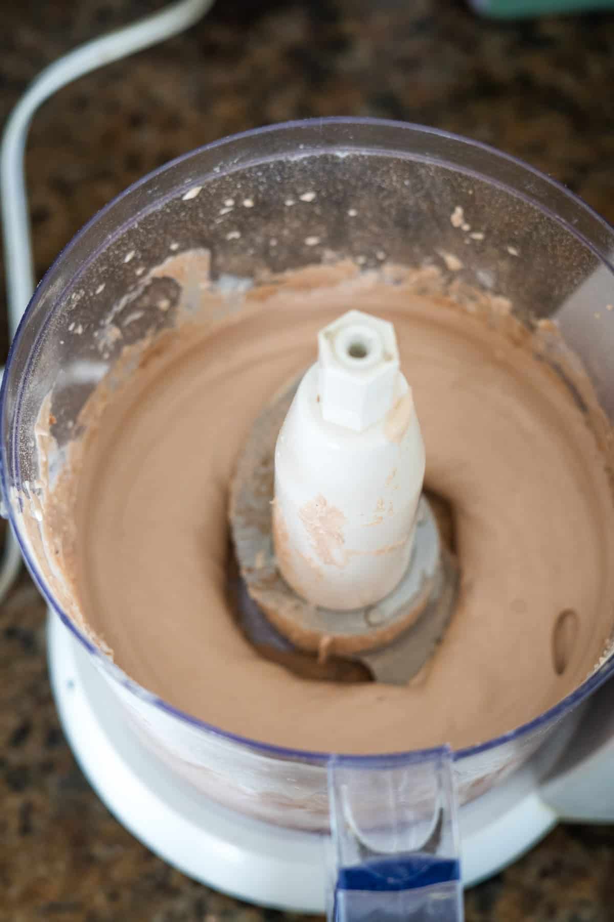 Top-down view of a food processor containing freshly processed creamy cottage cheese pudding.