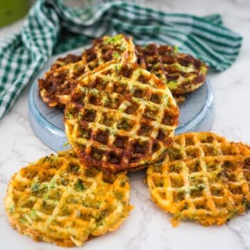 Savory waffles with vegetables served on a ceramic plate with a striped napkin on the side.