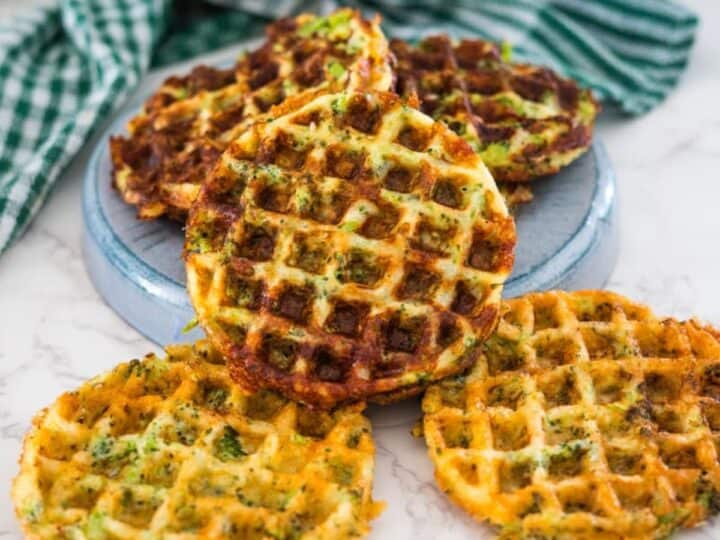 Savory waffles with vegetables served on a ceramic plate with a striped napkin on the side.