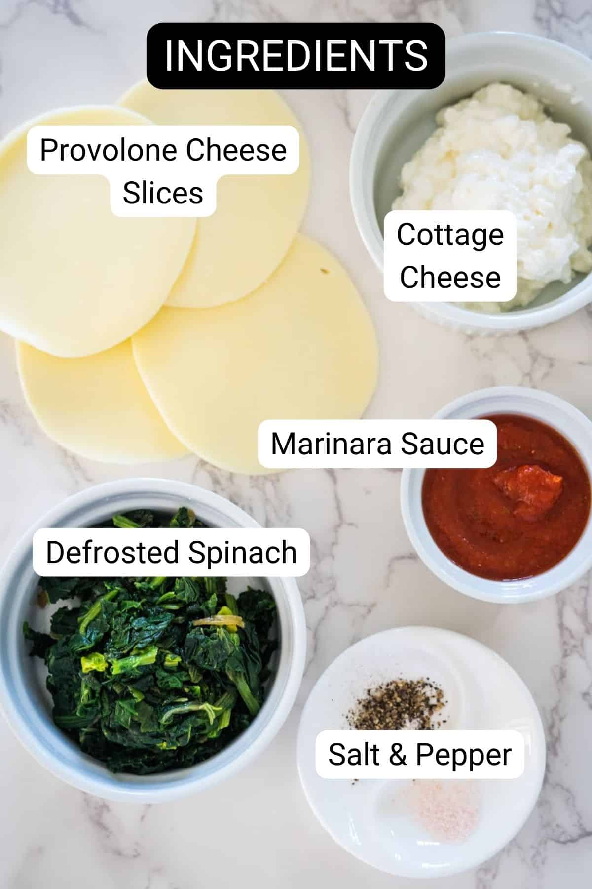 Ingredients for a recipe displayed: provolone slices, cottage cheese, marinara sauce, defrosted spinach, and salt & pepper, all in separate bowls on a marble countertop.