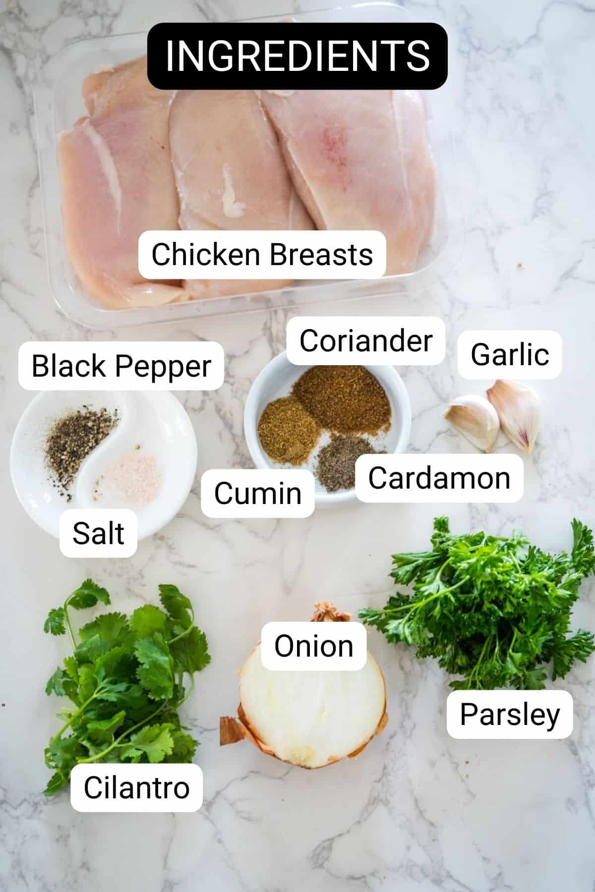 Ingredients for a recipe, including chicken breasts, coriander, garlic, black pepper, cumin, cardamom, salt, an onion, cilantro, and parsley, laid out on a marble surface.