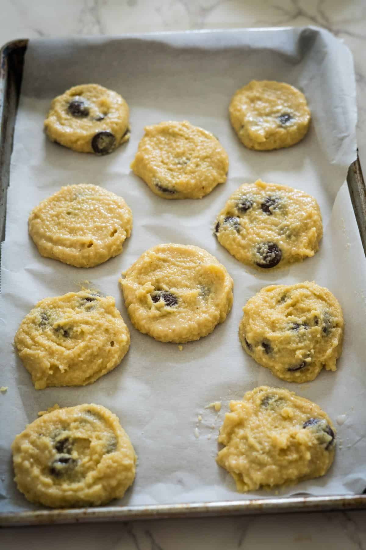 Unbaked chocolate chip cottage cheese cookies on a parchment-lined baking sheet.