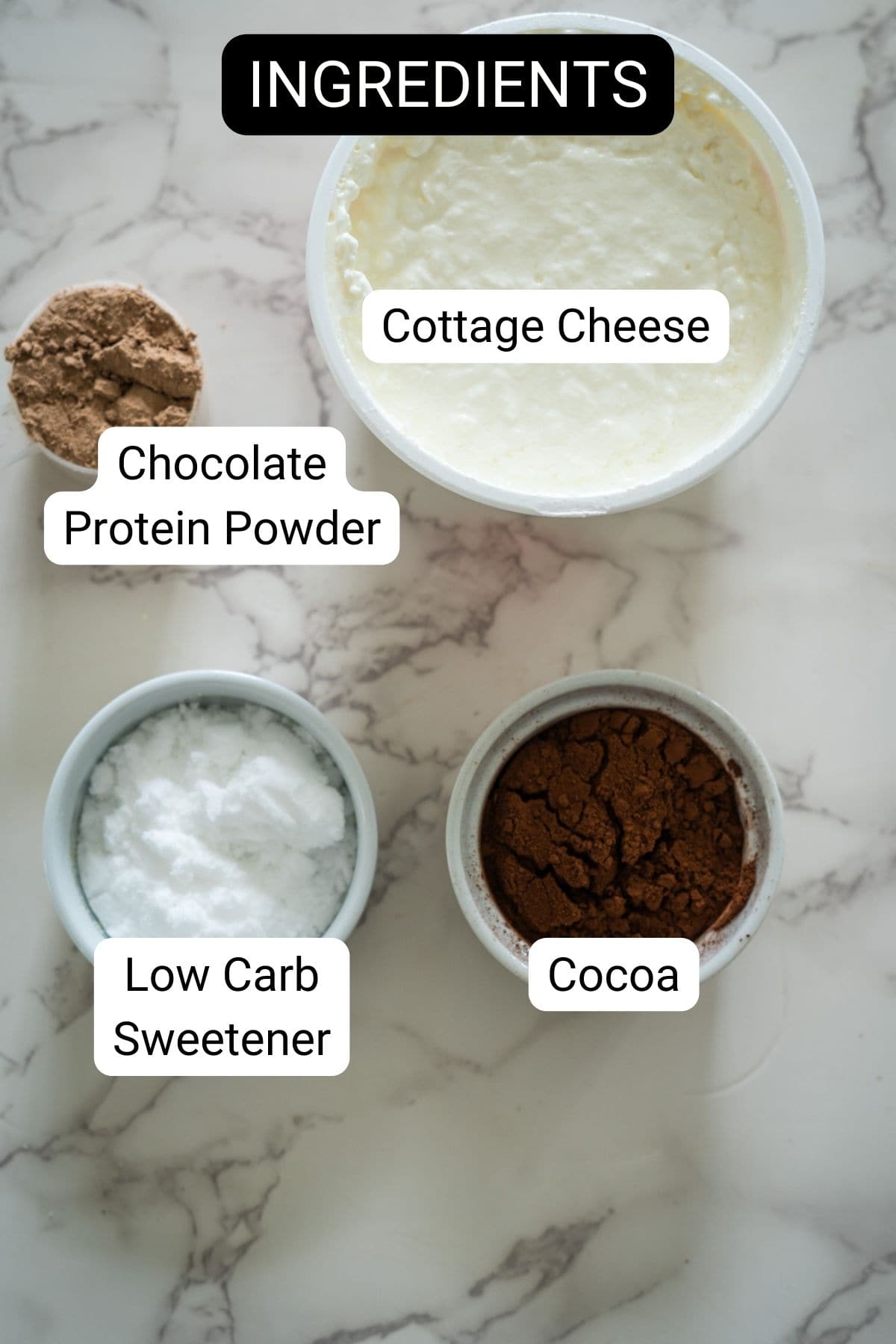 Labeled ingredients on a marble surface: cottage cheese, chocolate protein powder, low carb sweetener, and cocoa.