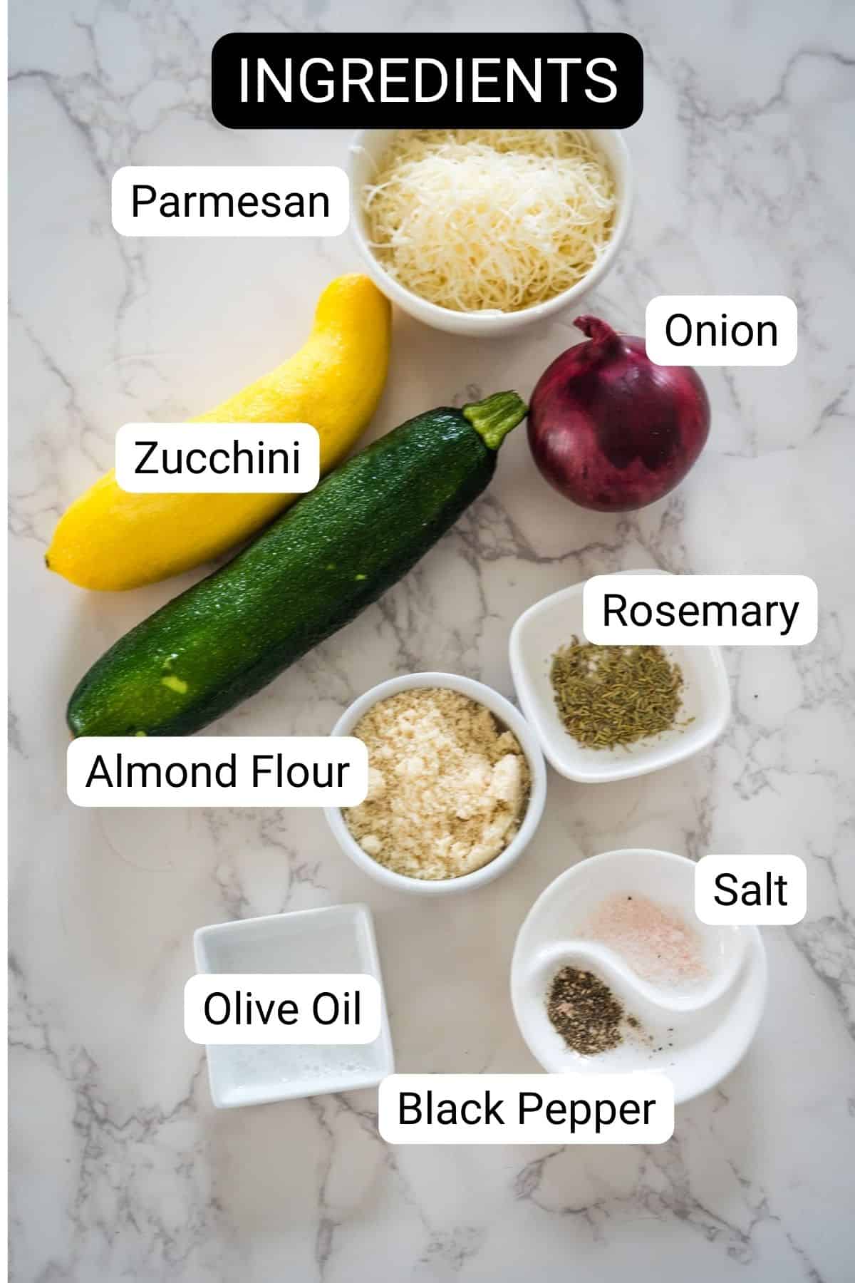 Ingredients including Parmesan cheese, zucchini, yellow squash, red onion, almond flour, rosemary, salt, black pepper, and olive oil arranged on a marble surface.