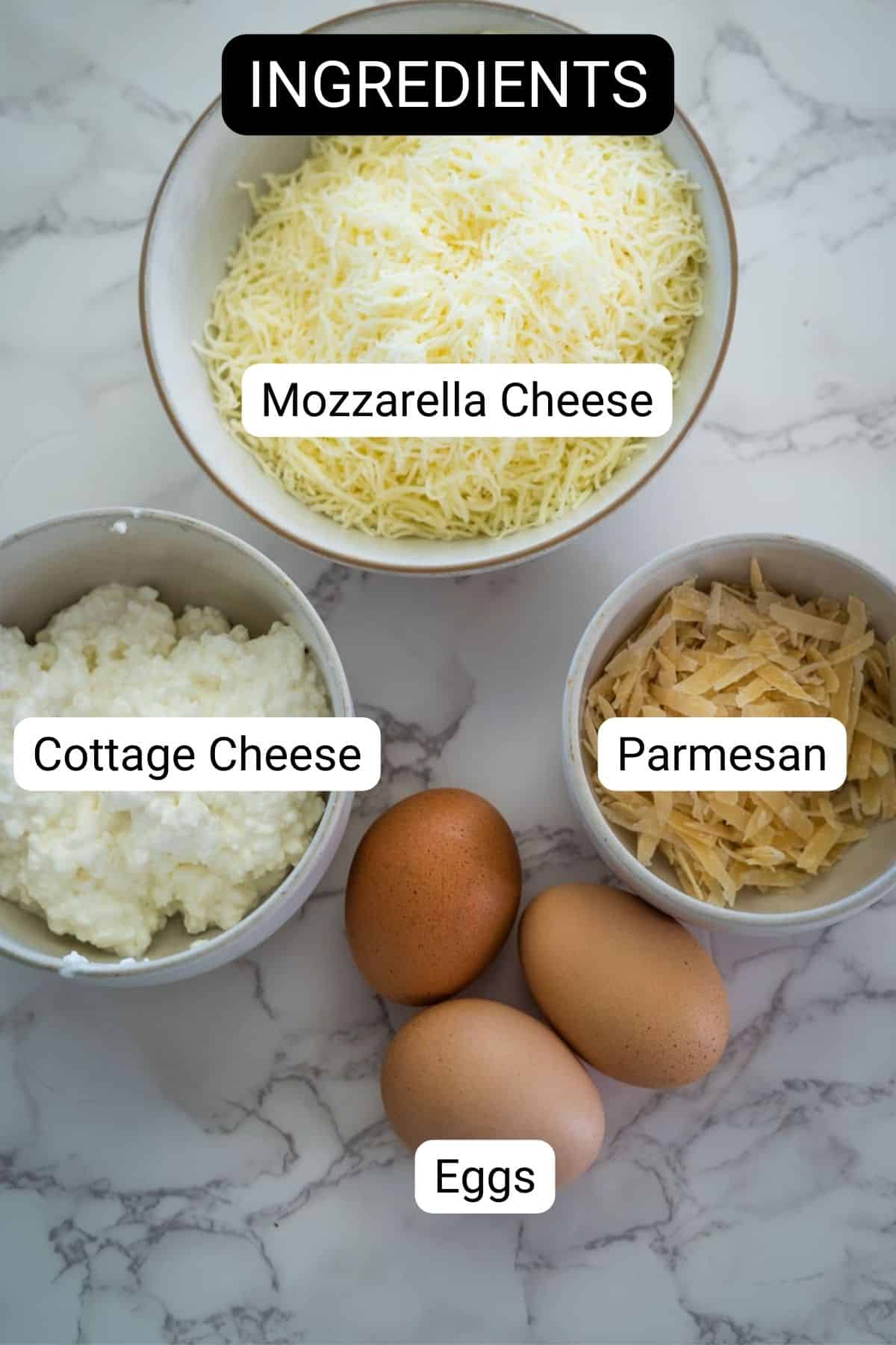 Three labeled bowls containing mozzarella cheese, cottage cheese, and parmesan cheese, along with three brown eggs arranged on a marble countertop—perfect for preparing keto lasagna noodles.