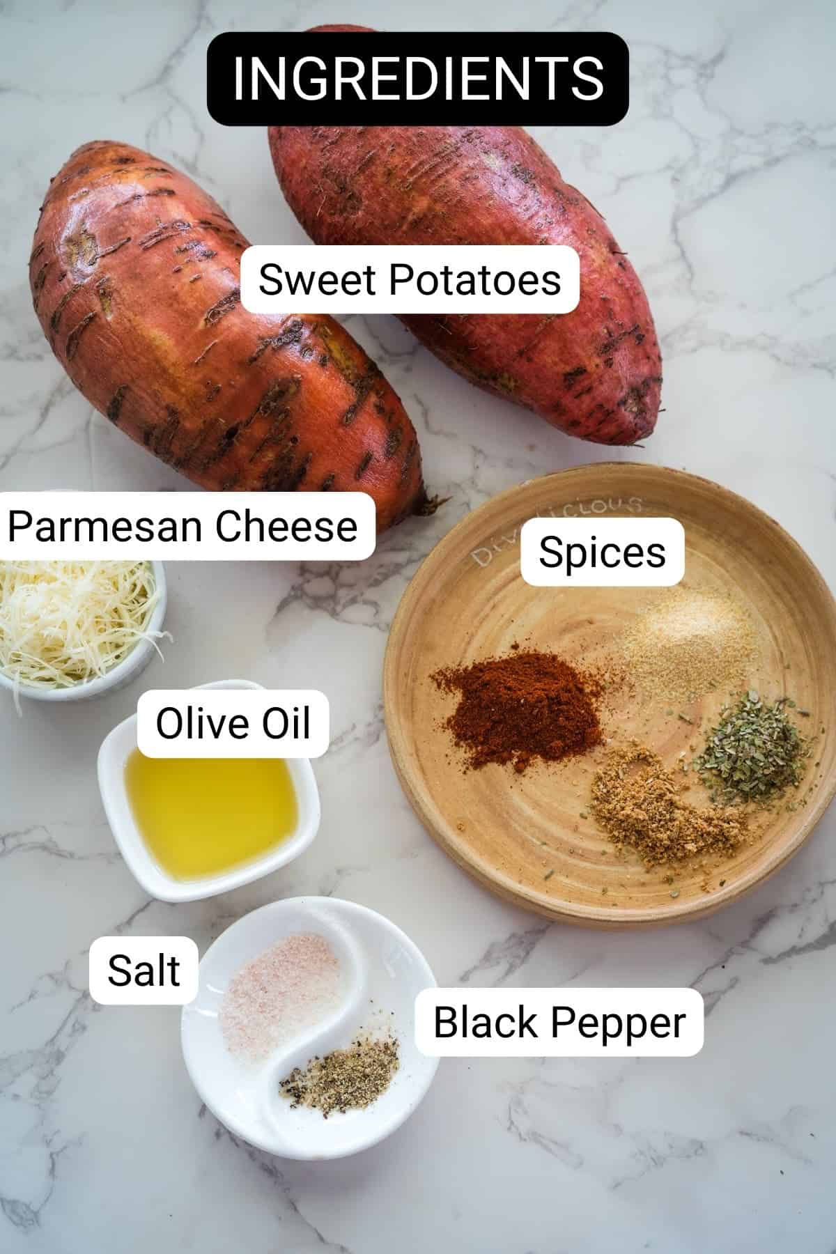 Overhead view of cooking ingredients labeled: sweet potatoes, parmesan cheese, spices, olive oil, salt, and black pepper arranged on a marble surface.