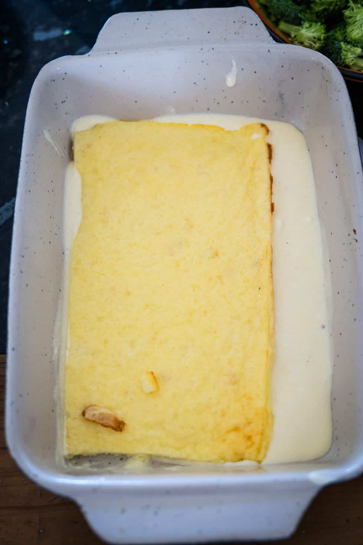 A rectangular piece of cooked polenta is placed in a white baking dish.