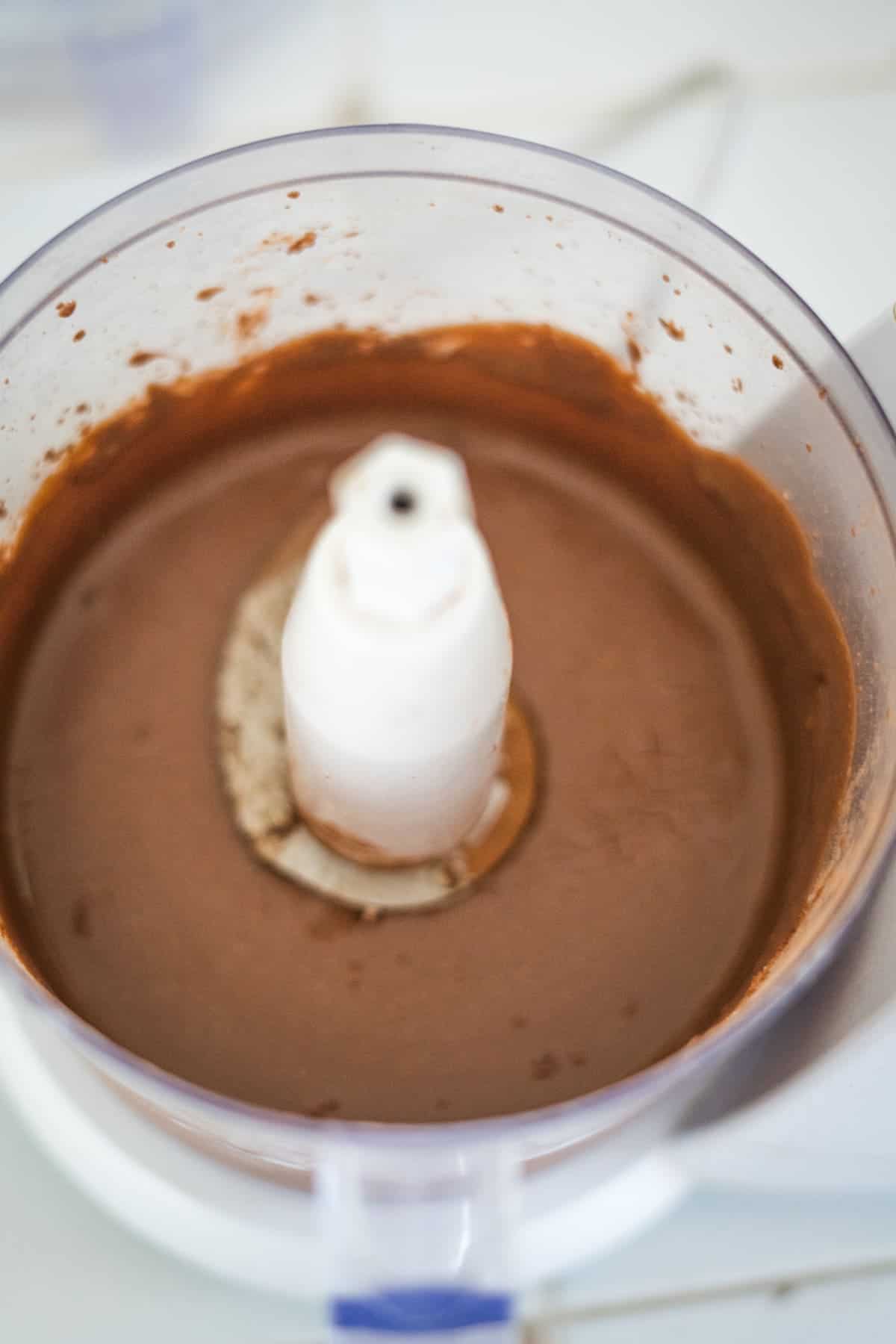 A food processor containing a smooth, chocolate mixture.