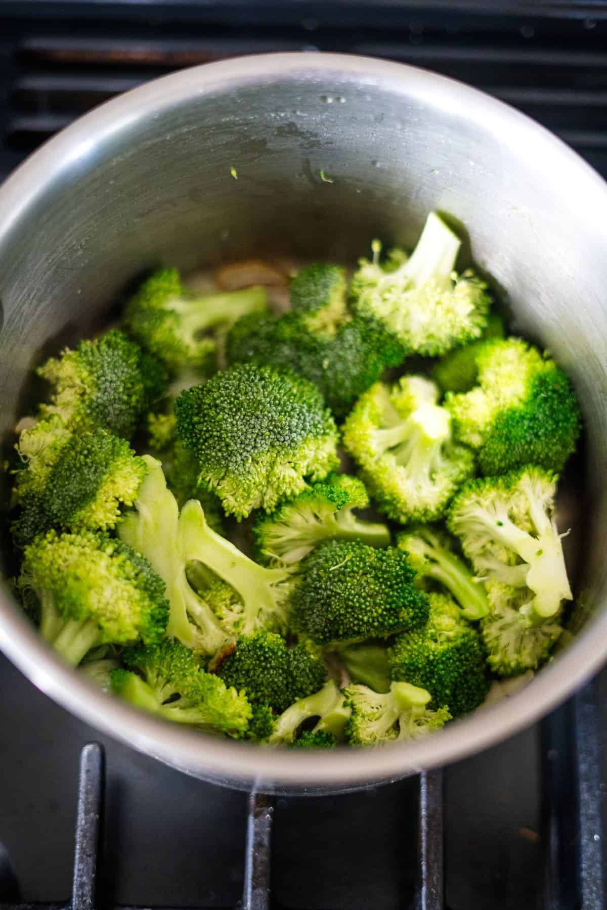 A pot filled with bright green broccoli florets on a stovetop.