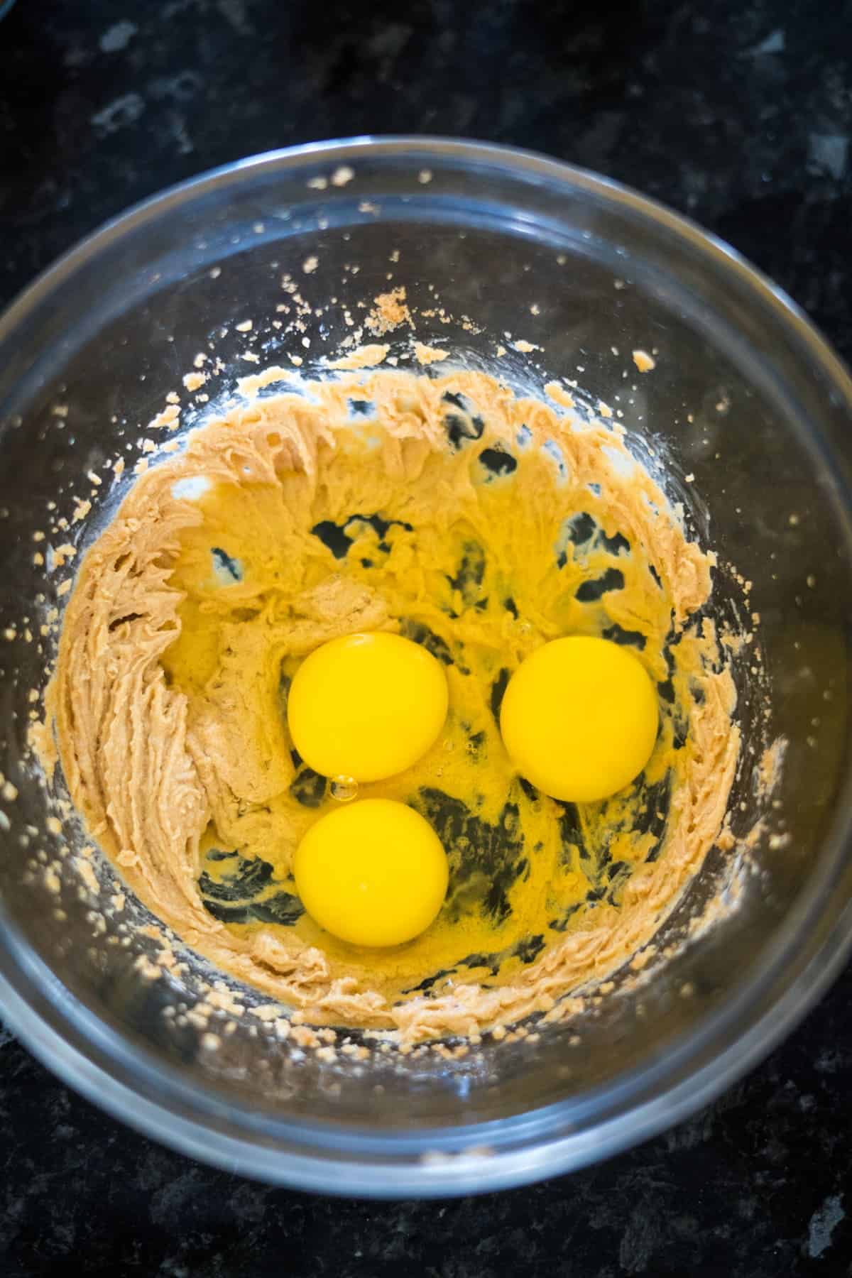 A mixing bowl with creamed butter and sugar, with three egg yolks added on top, ready to transform into delicious keto pumpkin cheesecake muffins.