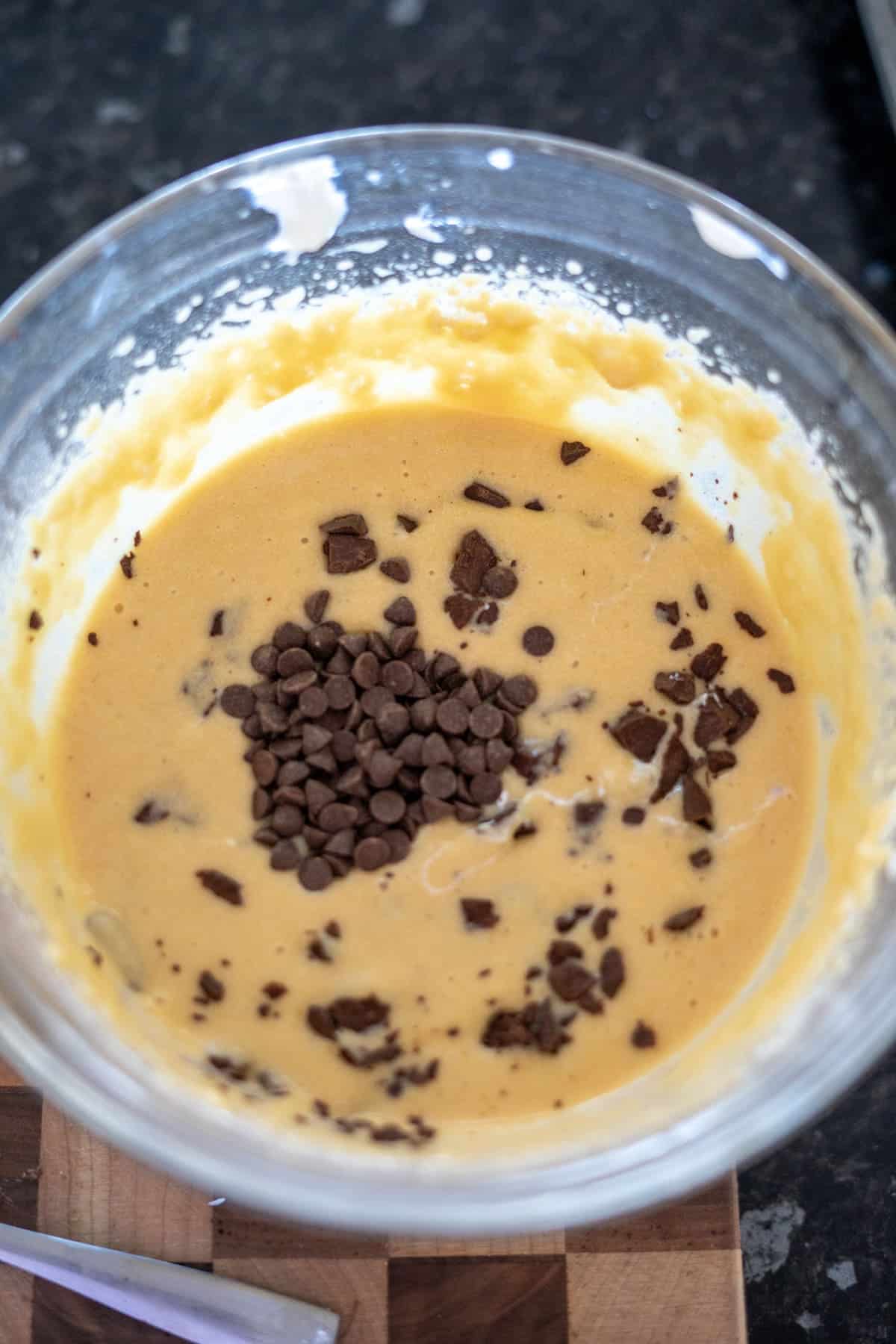 A glass bowl with cookie dough mixed with chocolate chips and chunks.