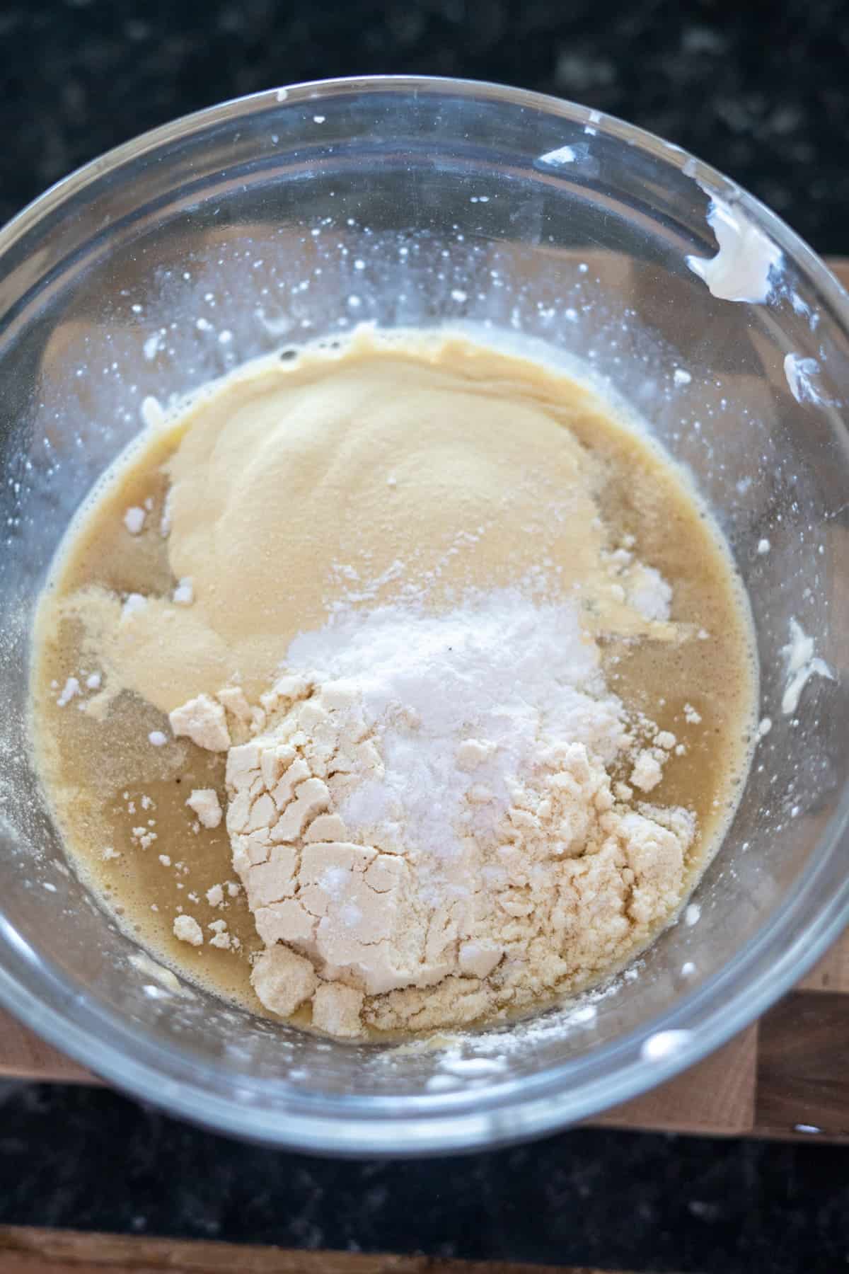 Bowl with flour, sugar, and liquid ingredients being mixed, viewed from above.