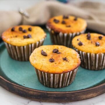 Four muffins with chocolate chips on a green plate.