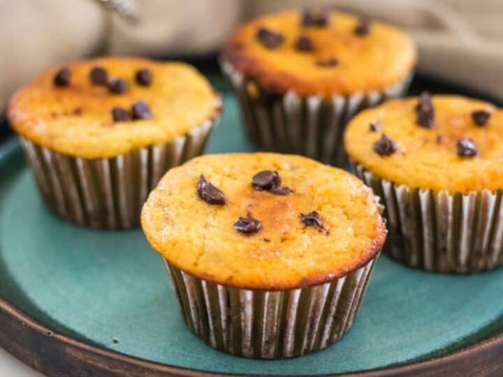 Four muffins with chocolate chips on a green plate.