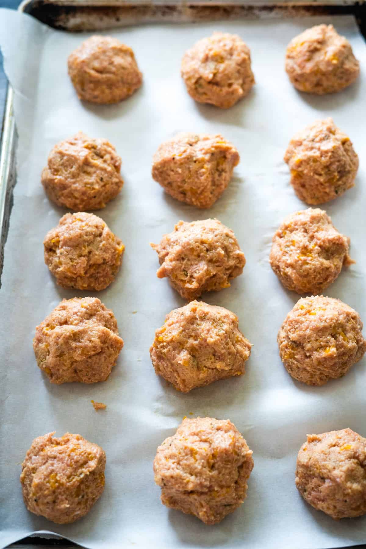 Raw dough balls on a parchment-lined baking sheet, ready for baking.