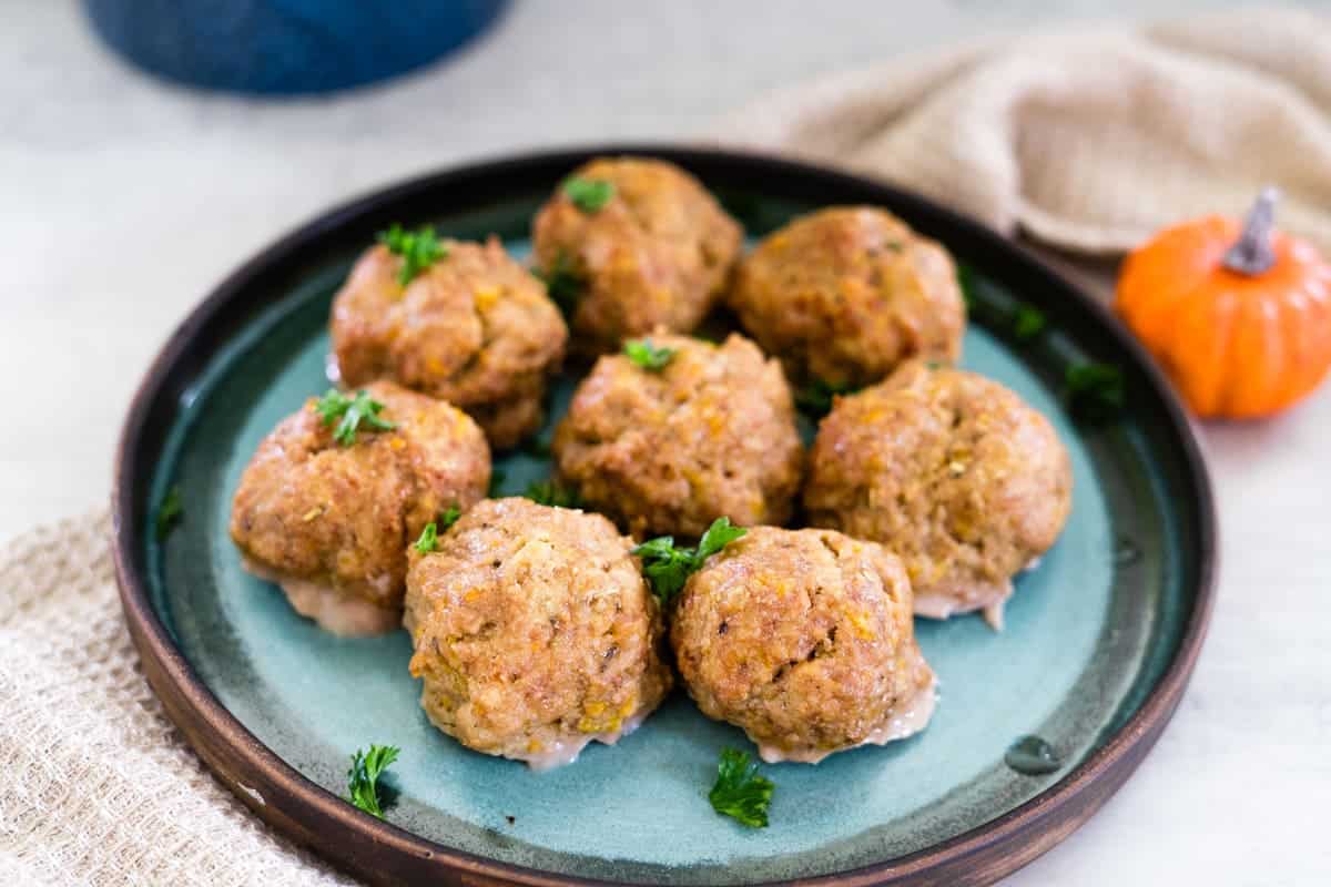 A plate of eight seasoned meatballs garnished with parsley, set on a blue ceramic dish.