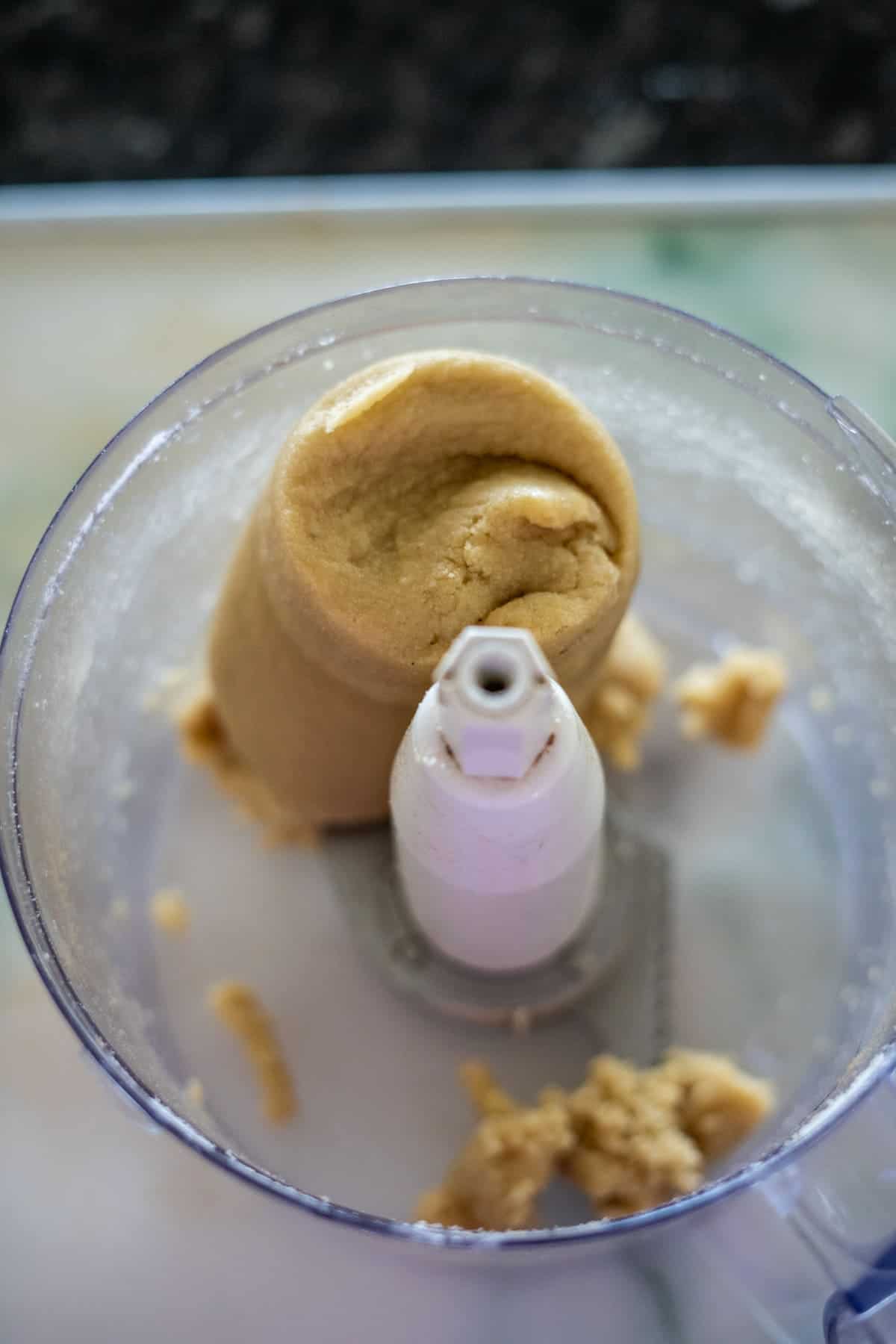 The food processor bowl held remnants of keto chocolate tart-inspired cookie dough, with some sticking stubbornly to the sides and a small amount resting at the bottom.