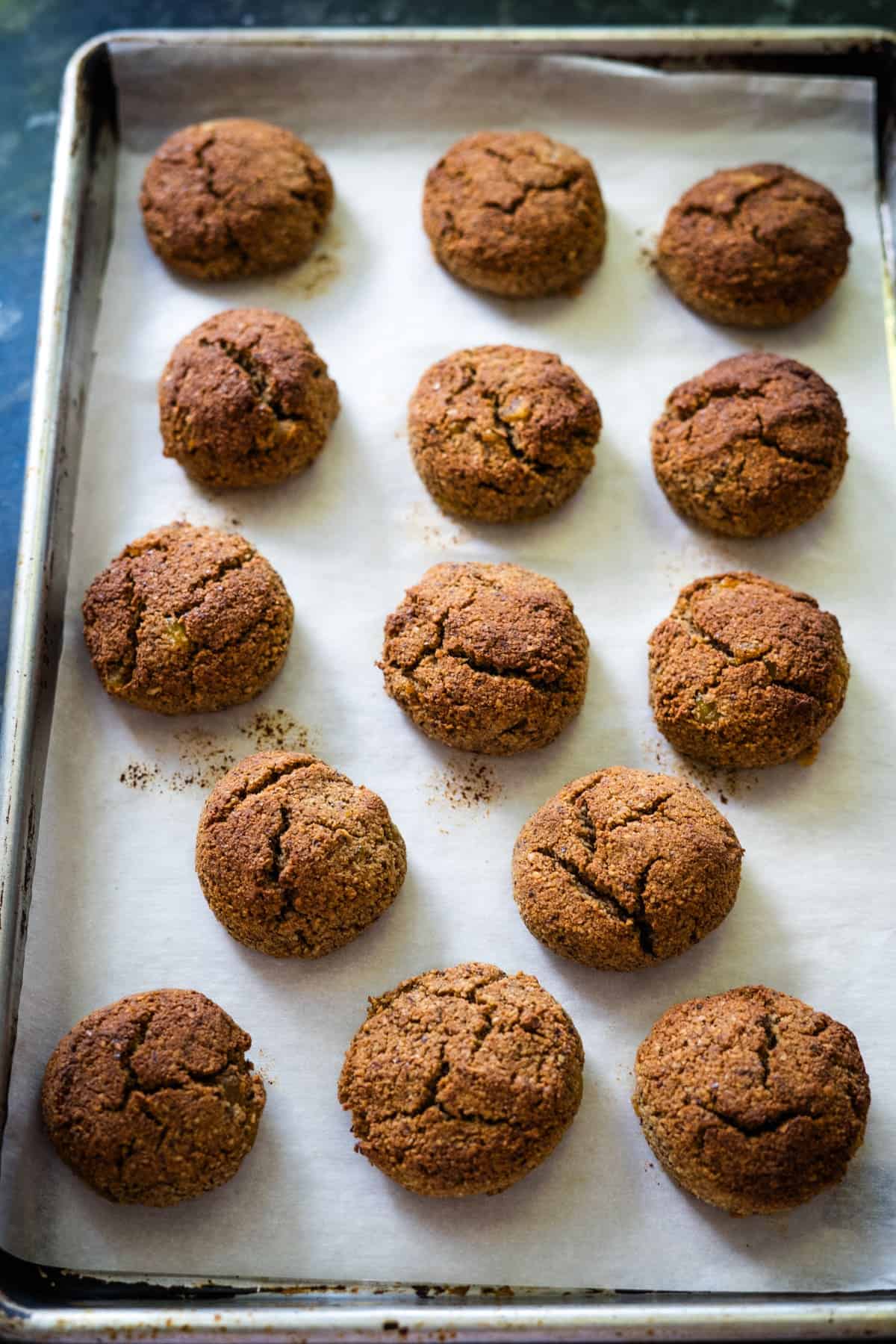 A baking tray with 15 round, brown cookies on parchment paper, these delightful treats are a low carb take on traditional lebkuchen, offering a guilt-free indulgence.