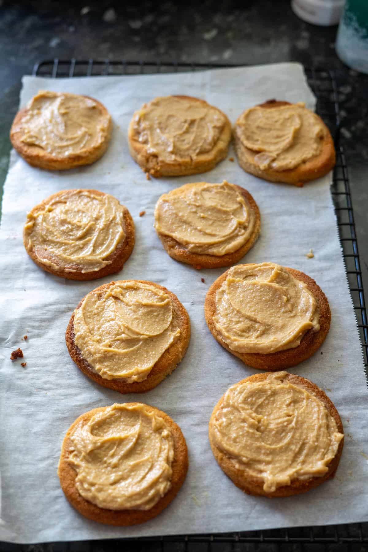 Eight keto cookies with brown frosting are arranged on parchment paper atop a cooling rack, reminiscent of a delicious Twix treat.