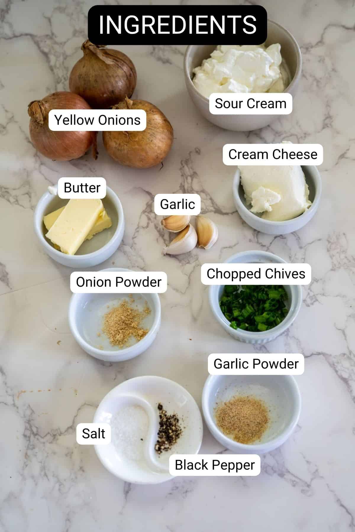 Labeled ingredients on a marble surface: yellow onions, sour cream, cream cheese, butter, garlic, onion powder, chopped chives, garlic powder, salt, and black pepper.