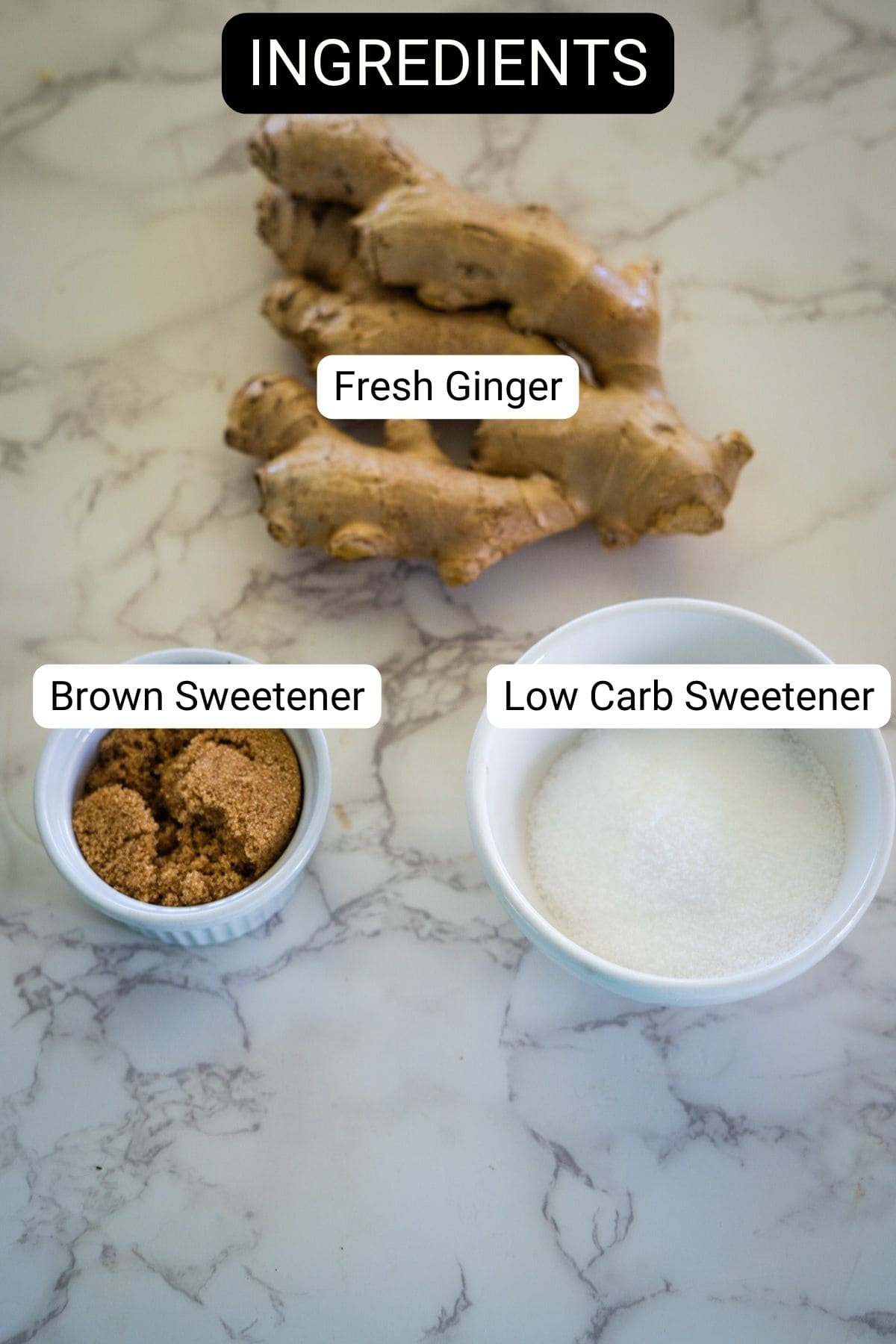 Fresh ginger, brown sweetener in a small bowl, and low carb sweetener in a larger bowl on a marble surface. Labels identify each ingredient.