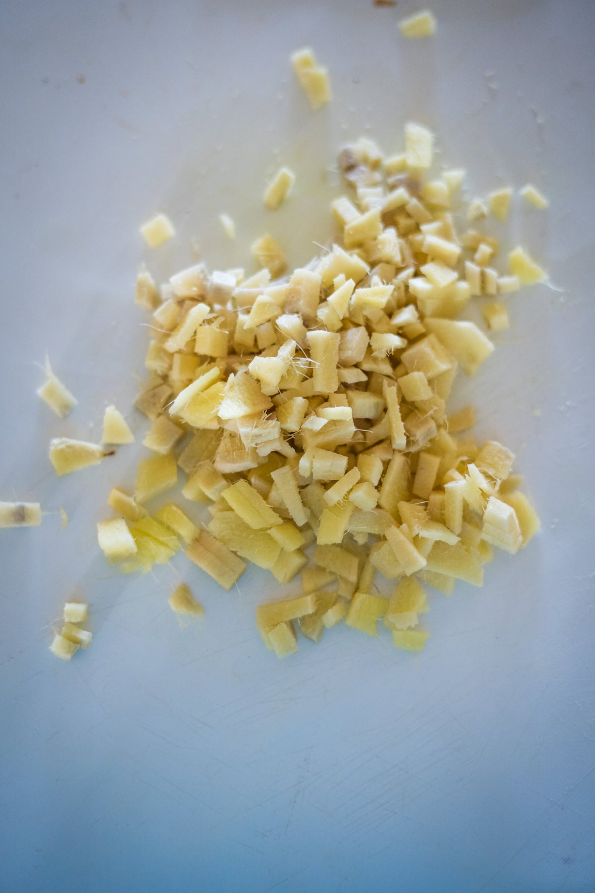 Diced ginger scattered on a white cutting board.