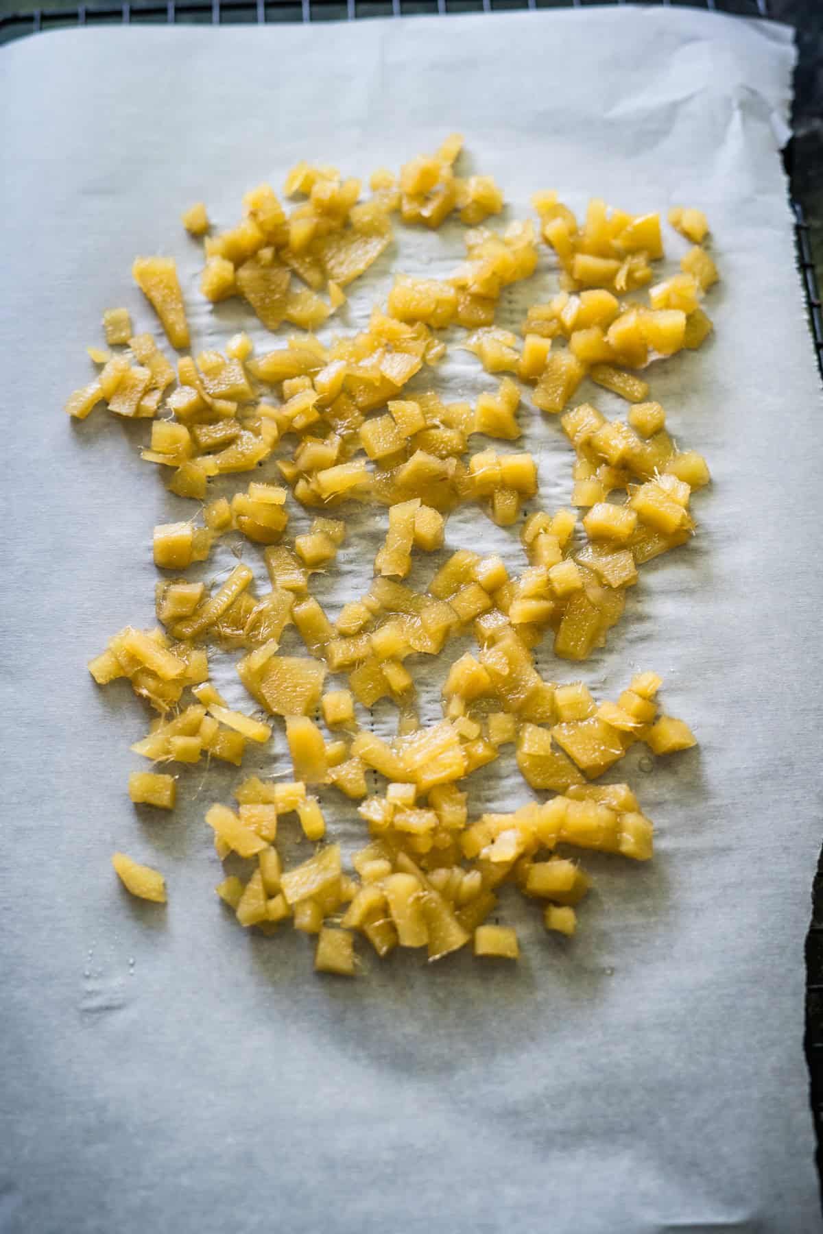 Diced yellow fruit spread on parchment paper on a cooling rack.