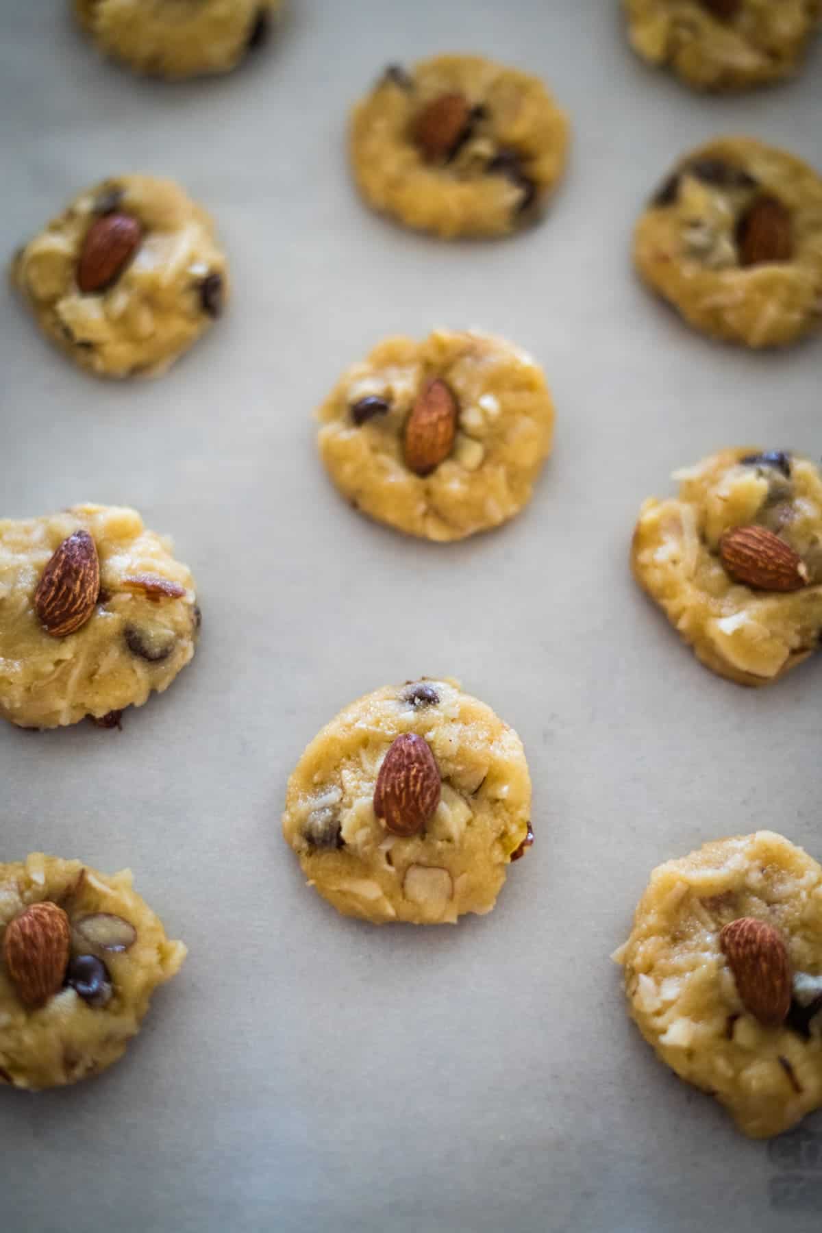 Unbaked cookie dough balls with almonds on a baking sheet.