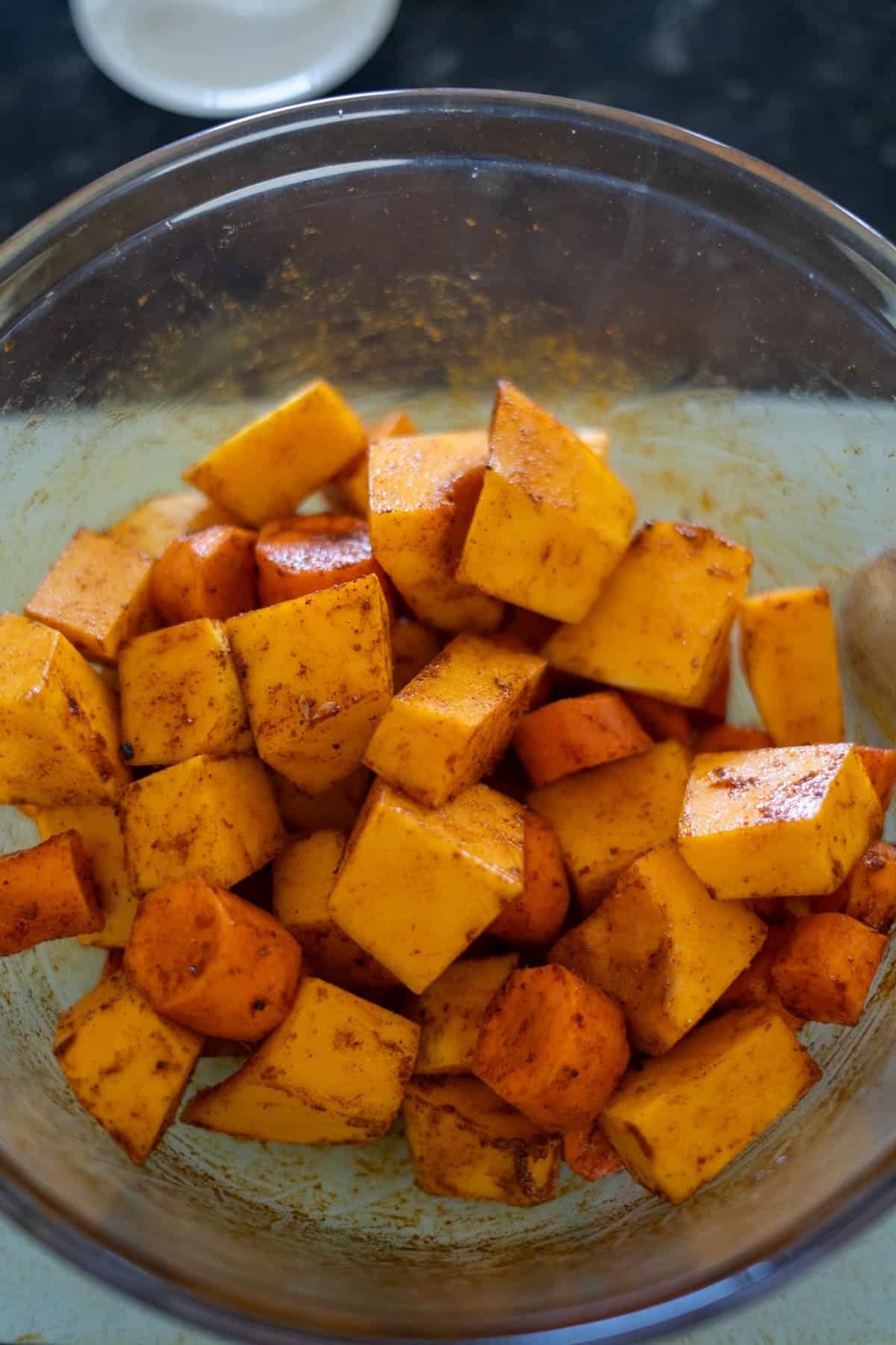 Cubes of butternut squash seasoned with spices mingle beautifully in a glass bowl, ready to elevate any dish or serve as the perfect base for a savory butternut squash and carrot soup.